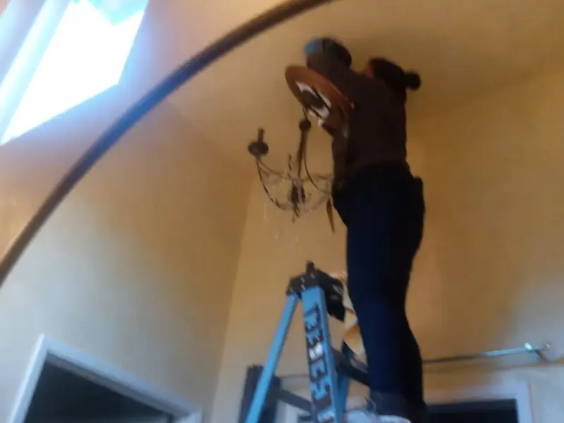 Electrician installing a chandelier in a Pierre residence